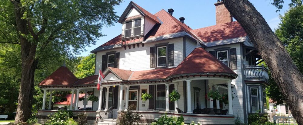View of the front of the inn. It's got a red roof with white siding and black shutters.