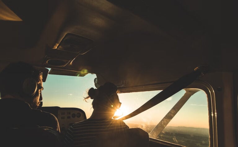 Two people in a helicopter at golden hour from the interior. They are silhouetted from behind looking down at the skyline of Ottawa.